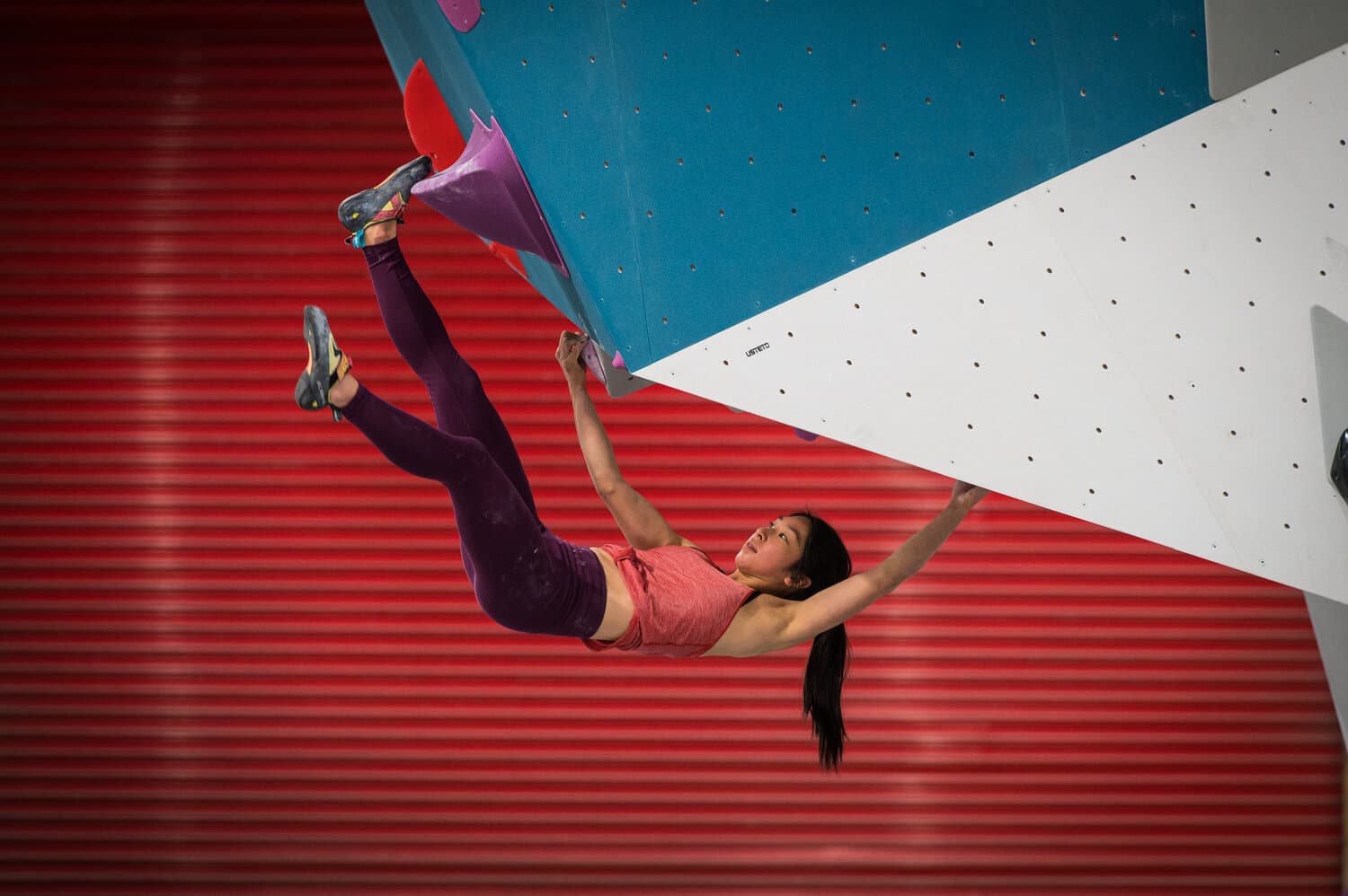 Woman on overhanging climb with bright contrasting background